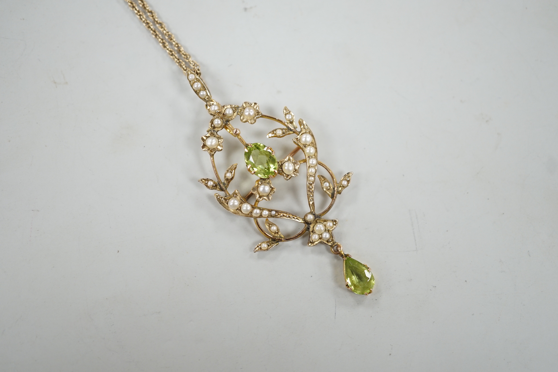 An Edwardian 9ct, peridot and seed pearl set drop pendant brooch, 57mm, on a later 375 rope twist chain, 44cm gross weight 6.7 grams.